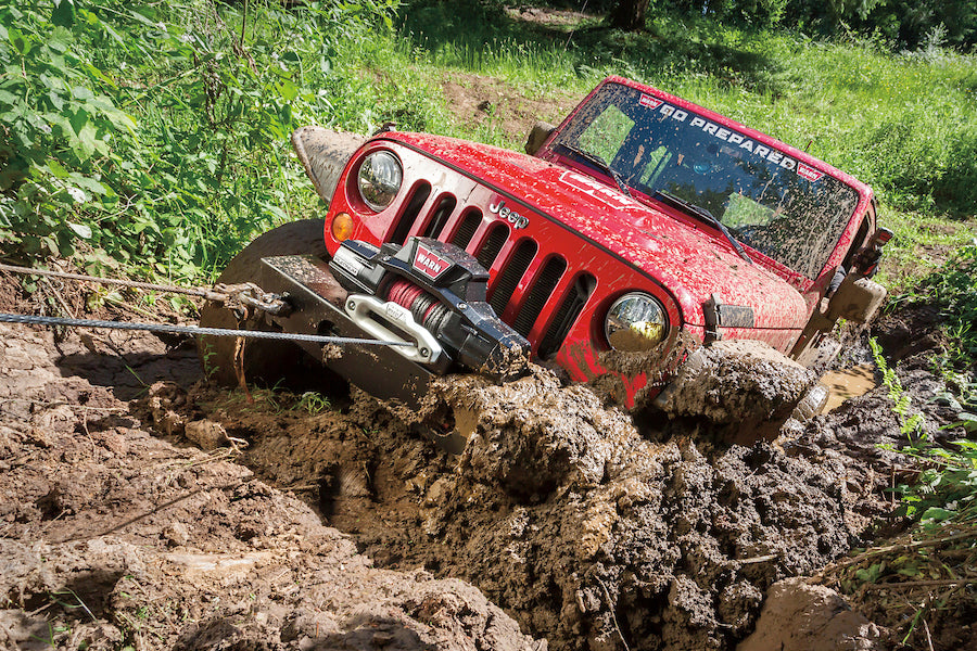 Geländewagen wird mit WARN Zeon 12S Platinum Seilwinde einen matschigen Hang hochgezogen